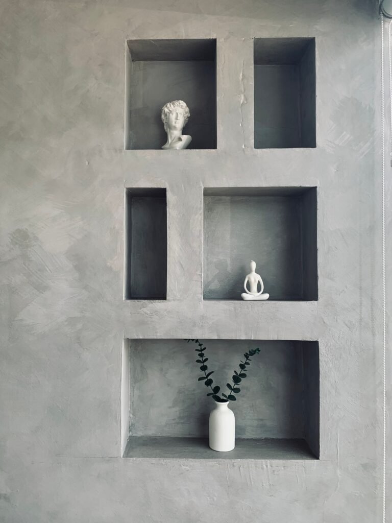 A minimalist wall design featuring decorative figurines and a vase in various niches.