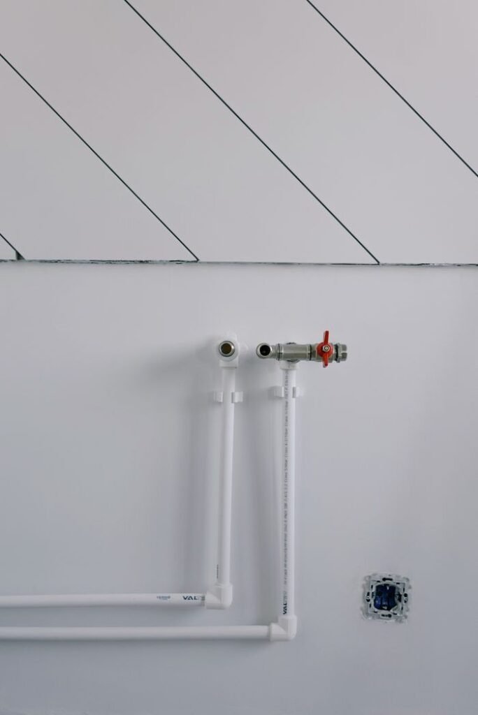 Long thin black slanted lines over pipes of radiator casting shadow on white wall in daytime